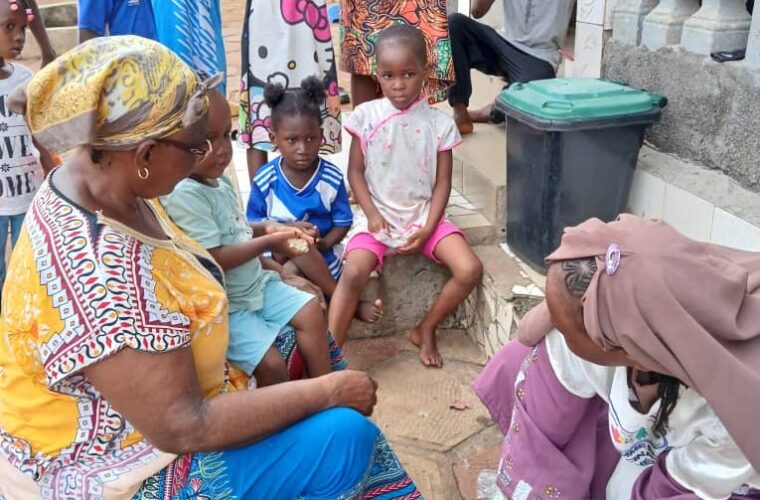Séance de vaccination de proximité : un agent prépare une dose depuis une glacière à vaccins, entouré d’enfants et de leurs mères.