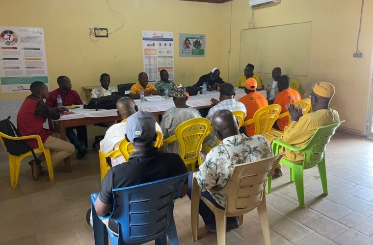 Assemblée communautaire du projet RACINE : une vingtaine de participants réunis en cercle dans une salle, devant des affiches de sensibilisation à la santé.