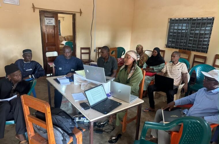 Réunion de travail du projet RACINE dans un bureau de la mairie de Timbo, autour d’une table équipée d’ordinateurs portables.